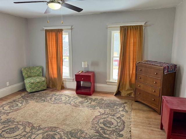 sitting room featuring baseboards, a ceiling fan, and wood finished floors