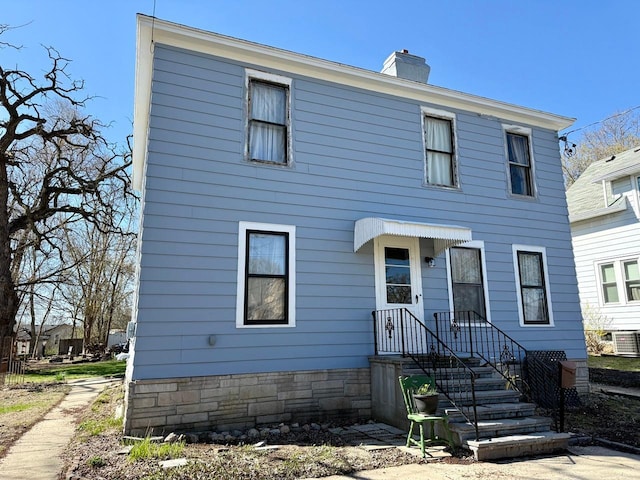view of front of property featuring a chimney and central AC unit