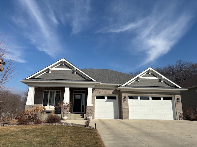 craftsman-style home with a garage, concrete driveway, a front lawn, a porch, and brick siding