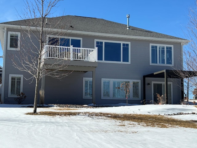 snow covered rear of property featuring a balcony