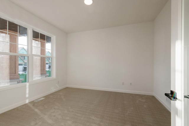 carpeted spare room with visible vents and baseboards