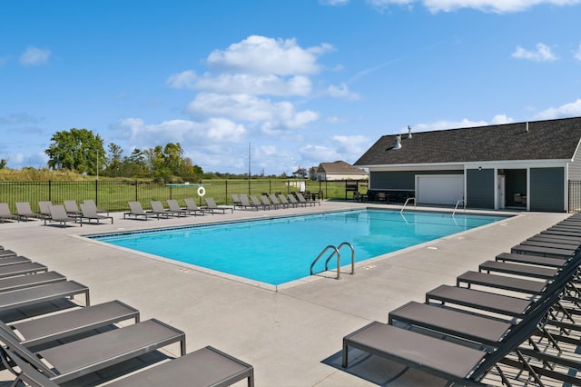 pool with a patio area and fence