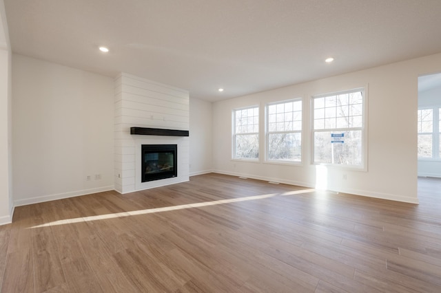 unfurnished living room with a fireplace, baseboards, wood finished floors, and recessed lighting