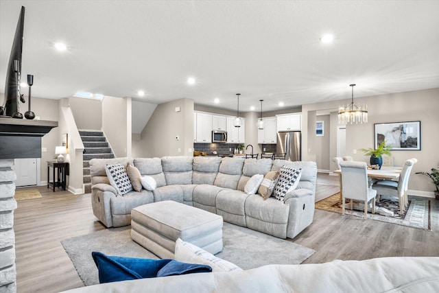 living room featuring light wood-style floors, recessed lighting, stairway, and an inviting chandelier