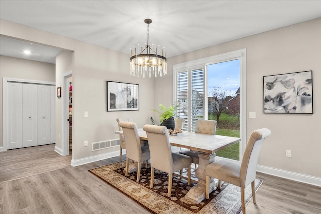 dining area with visible vents, a notable chandelier, baseboards, and wood finished floors