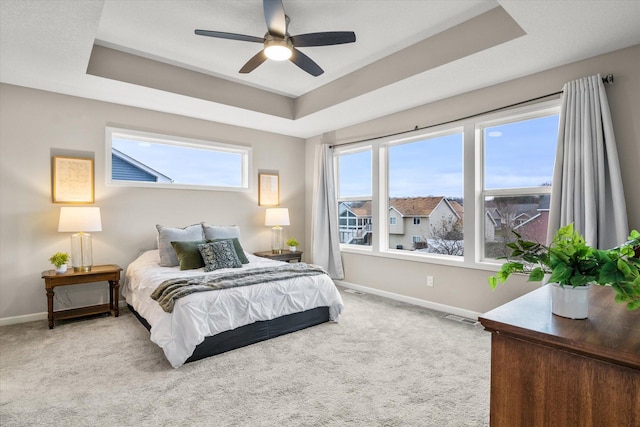 carpeted bedroom with a tray ceiling, visible vents, ceiling fan, and baseboards