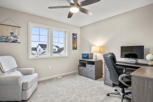 office featuring baseboards, ceiling fan, visible vents, and light colored carpet