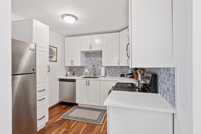 kitchen featuring dark wood-style floors, a sink, light countertops, appliances with stainless steel finishes, and backsplash