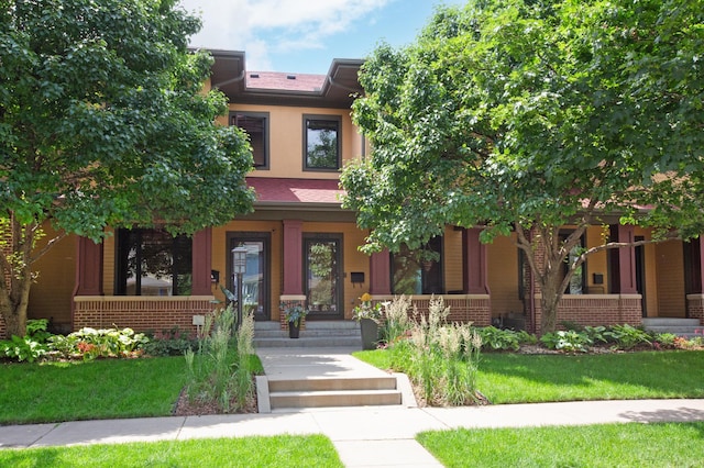 view of front of home featuring a front yard, covered porch, and stucco siding