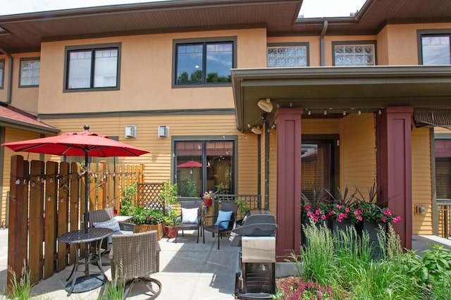 rear view of house featuring fence, a patio, and stucco siding