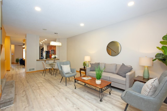 living area with recessed lighting, baseboards, visible vents, and light wood finished floors