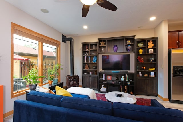 living room with baseboards, recessed lighting, a wood stove, and a ceiling fan