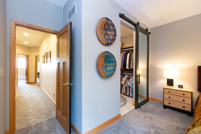 corridor with carpet, a barn door, visible vents, and baseboards