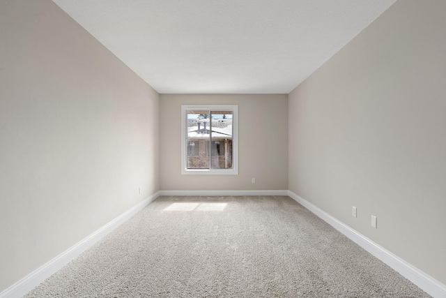 spare room featuring light carpet and baseboards