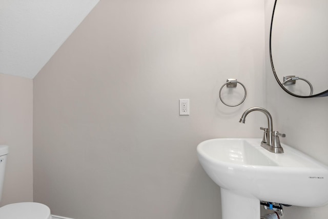 half bath with toilet, baseboards, and a sink