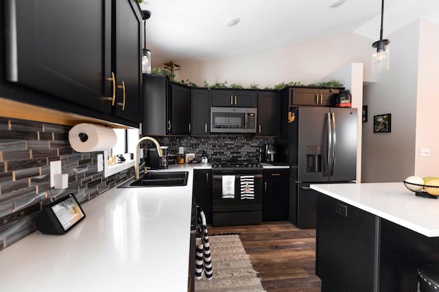 kitchen featuring dark wood-style flooring, a sink, vaulted ceiling, light countertops, and appliances with stainless steel finishes