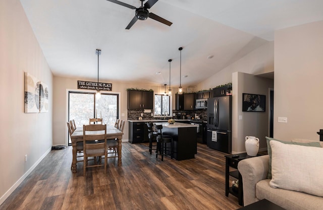 dining area with a ceiling fan, dark wood-type flooring, baseboards, and vaulted ceiling