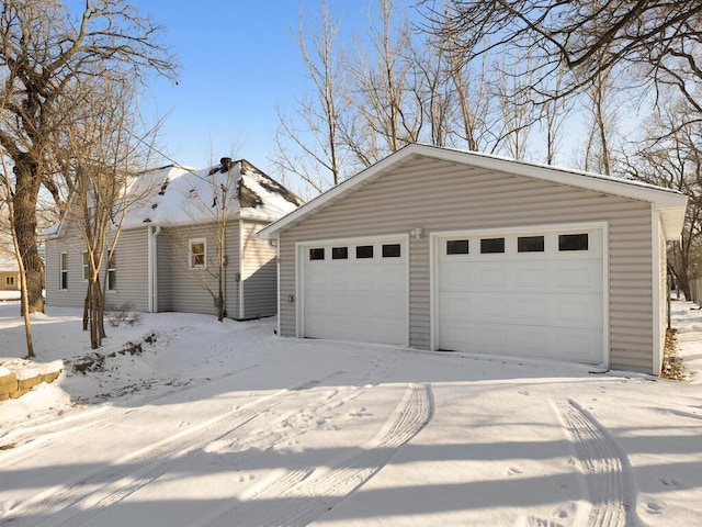 snow covered garage with a detached garage