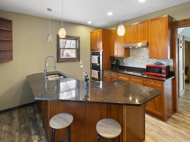 kitchen featuring double oven, brown cabinetry, and a sink