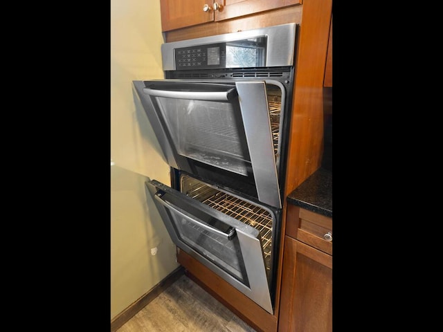 kitchen featuring brown cabinetry, light wood-type flooring, oven, and baseboards