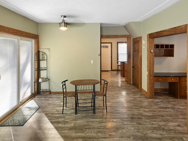 dining room with a textured ceiling, baseboards, and dark wood-type flooring