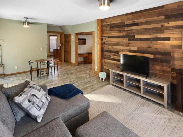 living room with wooden walls, baseboards, and wood finished floors