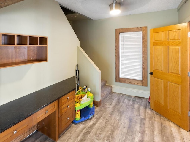 game room featuring built in study area, light wood-style flooring, and baseboards