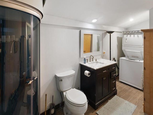 bathroom with recessed lighting, toilet, vanity, stacked washing maching and dryer, and wood finished floors