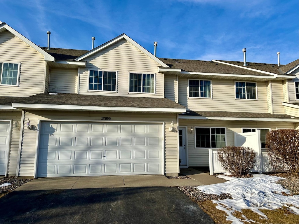 multi unit property featuring aphalt driveway, a garage, and roof with shingles