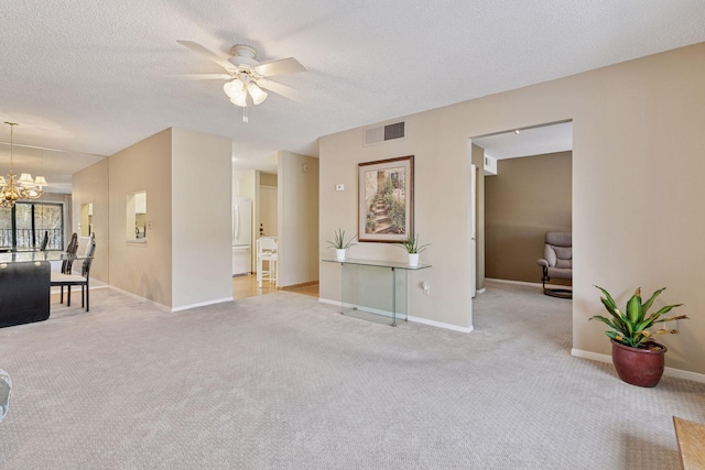 carpeted living area featuring ceiling fan with notable chandelier, baseboards, visible vents, and a textured ceiling