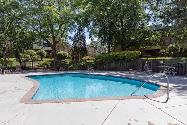 pool with a patio area and fence