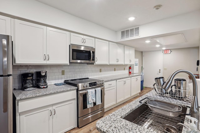 kitchen with light wood finished floors, visible vents, appliances with stainless steel finishes, and white cabinetry