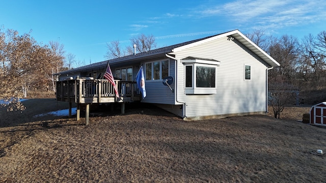 view of property exterior with an outbuilding, a deck, and a storage unit