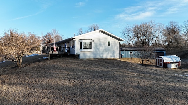 view of side of home with a wooden deck, a storage unit, and an outdoor structure