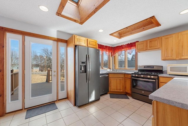 kitchen with a sink, a textured ceiling, recessed lighting, stainless steel appliances, and a skylight