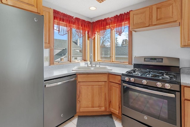 kitchen with a sink, light countertops, light tile patterned flooring, and stainless steel appliances