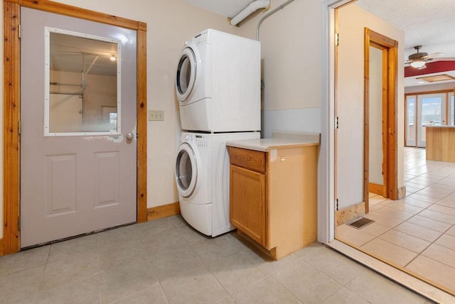 laundry room with light tile patterned floors, cabinet space, ceiling fan, and stacked washer / dryer