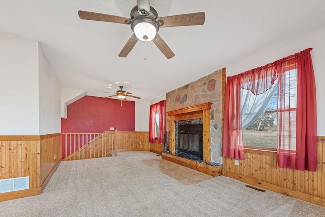 unfurnished living room with visible vents, carpet, a wainscoted wall, and wood walls