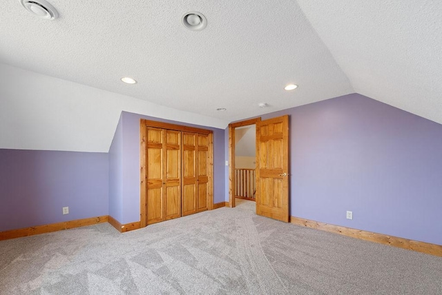 additional living space with carpet floors, a textured ceiling, baseboards, and vaulted ceiling