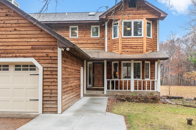 view of front of property with a porch, a shingled roof, and an attached garage