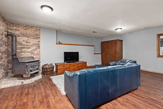 living area with a wood stove, visible vents, baseboards, and wood finished floors