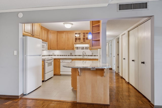 kitchen featuring light stone counters, visible vents, decorative backsplash, a sink, and white appliances