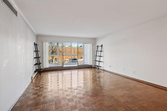 empty room featuring visible vents, crown molding, a textured ceiling, and baseboards