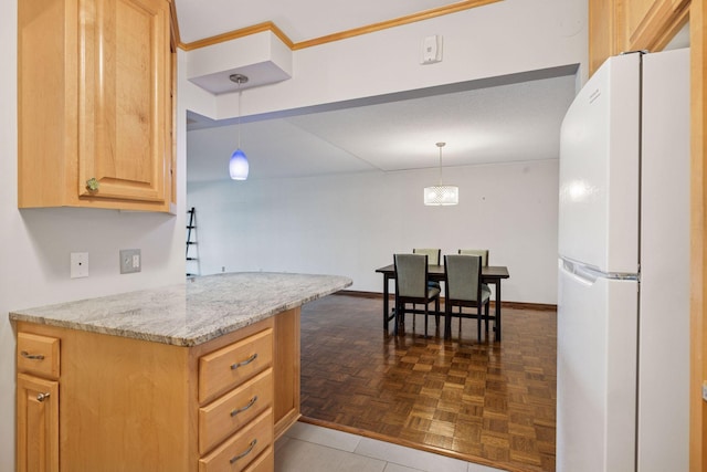 kitchen featuring hanging light fixtures, light brown cabinetry, freestanding refrigerator, light stone countertops, and baseboards