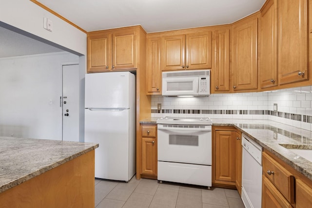 kitchen featuring tasteful backsplash, light stone countertops, white appliances, and light tile patterned floors