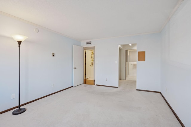 spare room featuring ornamental molding, light colored carpet, visible vents, and baseboards