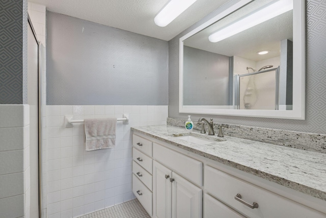 full bathroom featuring vanity, wainscoting, a shower stall, and tile walls