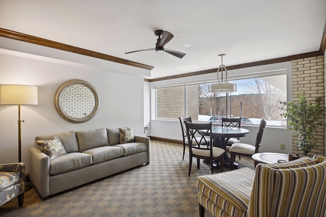 living area with dark colored carpet, crown molding, baseboards, and ceiling fan