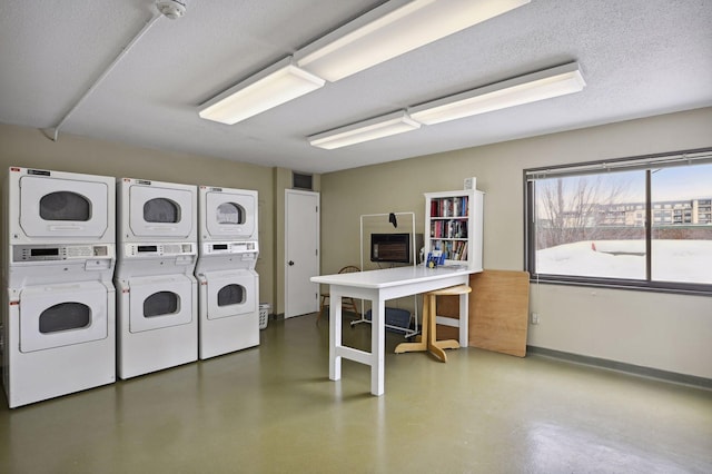 shared laundry area featuring a textured ceiling, stacked washer and clothes dryer, and baseboards