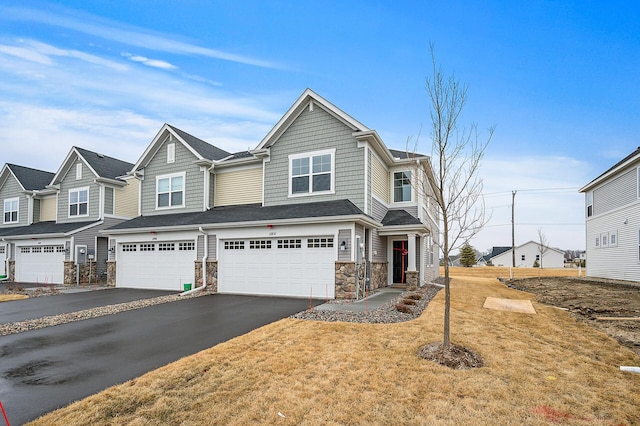 view of front of house with aphalt driveway, a residential view, stone siding, and an attached garage